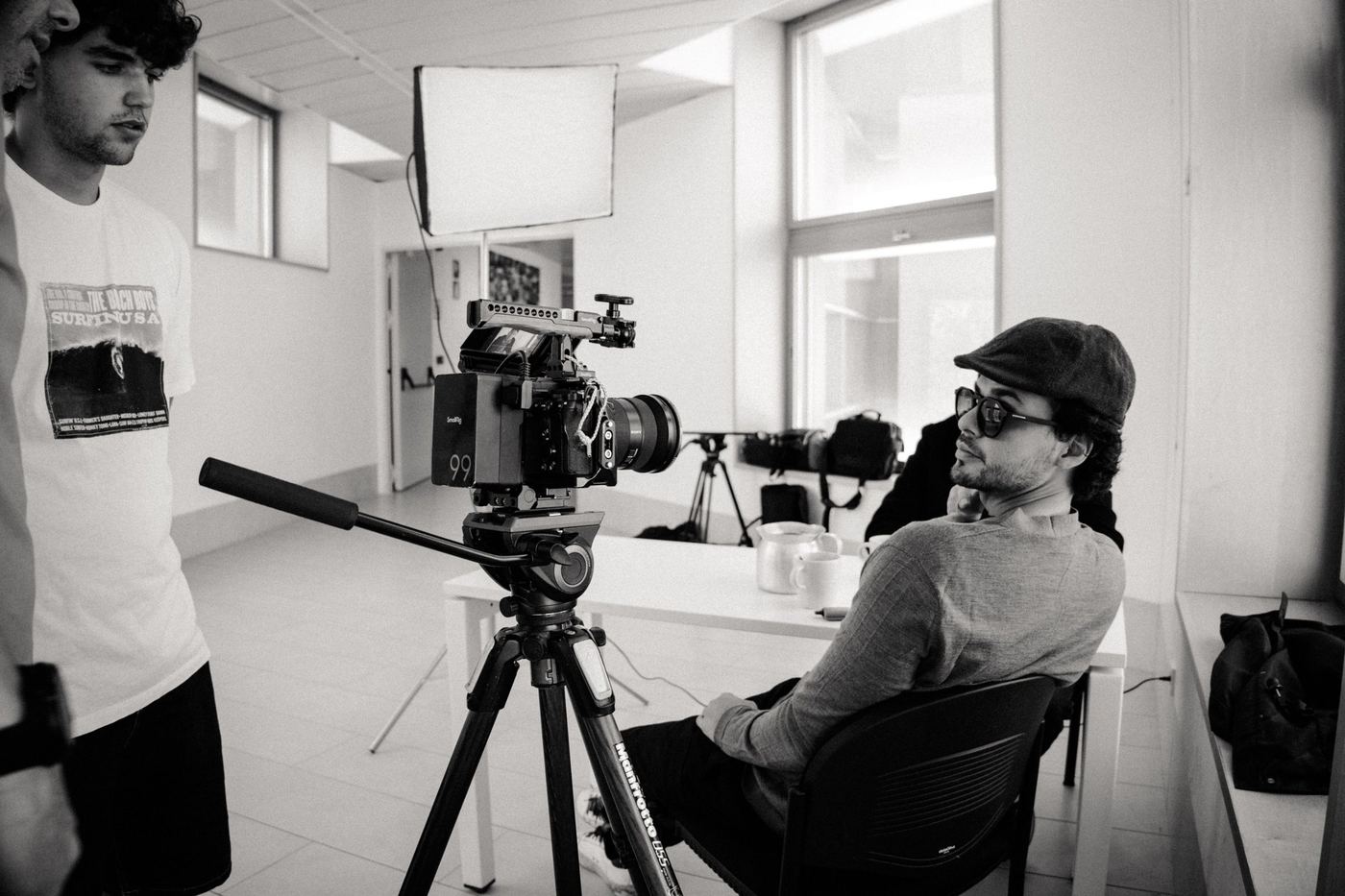 Cámara de cine sobre tripié en un set con luz de ventana, blanco y negro