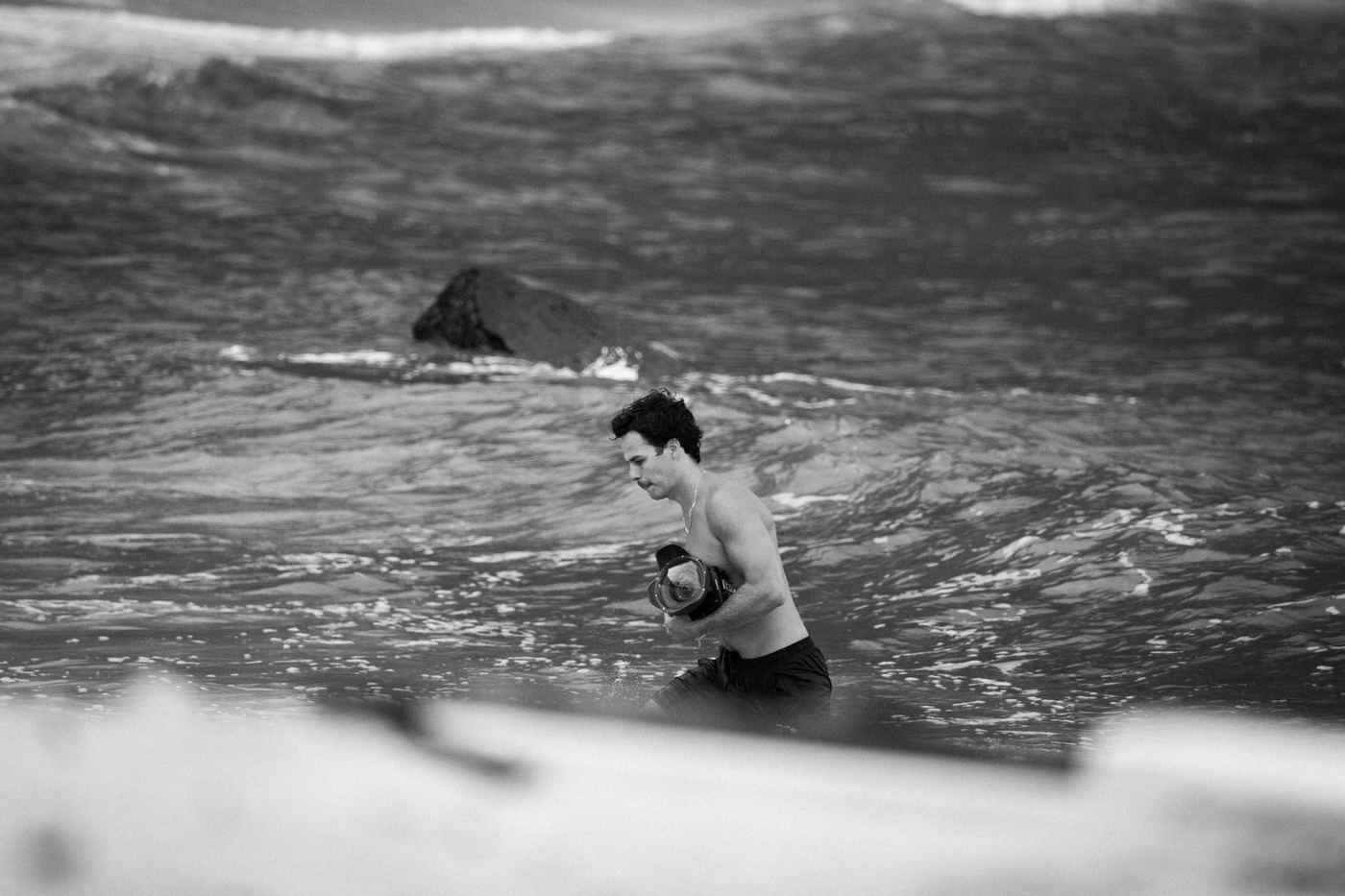 Persona dentro del mar con una cámara en carcasa, blanco y negro